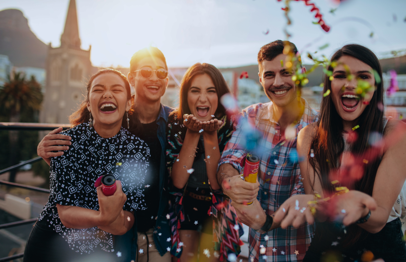 Groep van vijf lachende mensen die confetti strooien